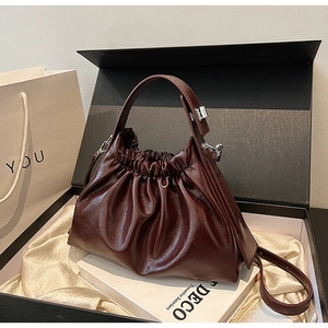 Detailed view of burgundy ruched cloud bag in a gift box with champagne silk lining