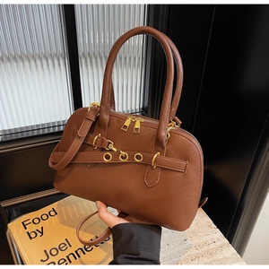 Detail of brown litchi leather bowling bag with gold hardware and adjustable strap