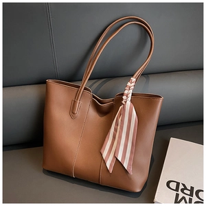 Close-up of brown tote bag with decorative striped scarf on a textured surface