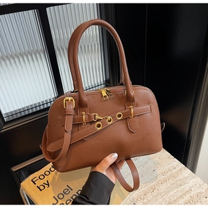 Close-up of vintage brown leather handbag with elegant gold hardware and zip detail