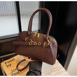 Detail view of brown leather handbag with gold buckle rings and adjustable strap
