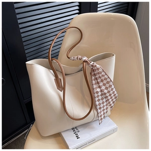 Detail of a minimalist tote bag in creamy white leather with checkered scarf on a chair