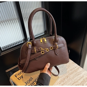 Close-up of brown Boston bag showing golden ring hardware and matte leather texture