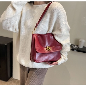 Close-up of burgundy oil-waxed leather handbag with a gold floral twist-lock clasp
