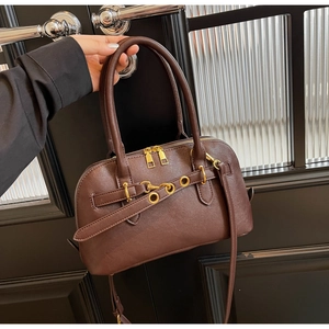 Detailed view of dark brown textured leather handbag with gold zippers and metal eyelet belt
