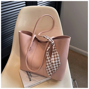 Pink faux leather tote bag detail with checkered silk scarf on a beige chair