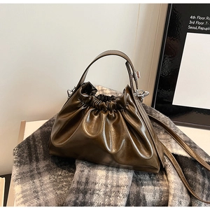 Detailed close-up of dark brown pleated handbag texture and glossy leather finish