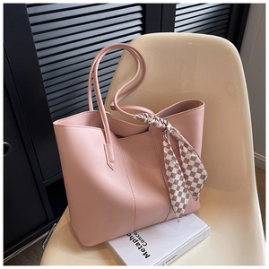 Detailed shot of pink faux leather tote bag with a checkered silk scarf on a modern chair