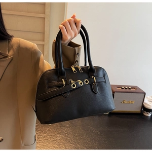 Detail of black pebbled leather handbag featuring gold hardware and classic handle design