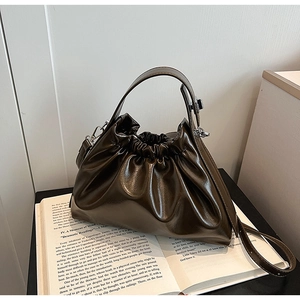 Detail of dark coffee ruched cloud bag showing glossy leather texture and soft folds