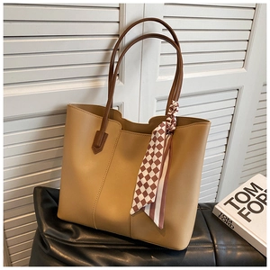 Detail of camel PU tote bag featuring brown shoulder straps and checkered silk scarf