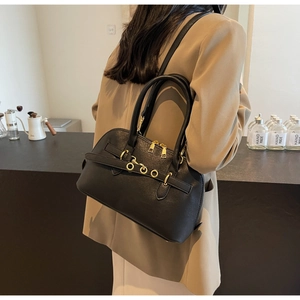 Detailed view of black leather half-round crossbody bag with golden rings on female model