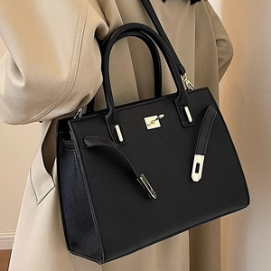 Borsa a mano trapezoidale nera in pelle martellata con chiusura dorata indossata dal modello