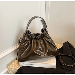 Close-up of a dark brown pleated cloud bag with textured leather and wide handle