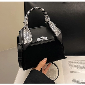 Detail of black matte leather Kelly bag with silver buckle and decorative silk scarf
