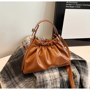 Brown pleated cloud bag in shiny PU leather on grey plaid scarf detail shot