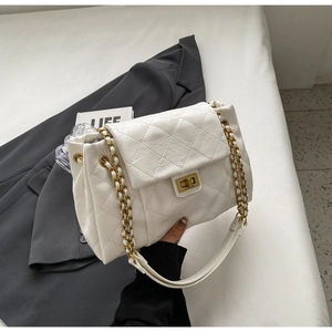 Detail of white quilted leather chain bag with golden lock on a grey suit jacket