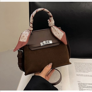 Detail of vintage matte leather Kelly bag featuring metallic twist lock and silk scarf handle