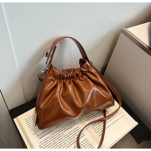 Close-up of brown ruched leather cloud bag placed on an open book for detail