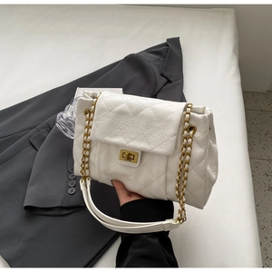 Close-up of white quilted leather texture and gold metal clasp on a crossbody bag
