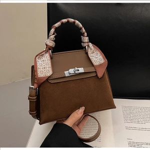 Detail view of dark brown trapezoid handbag with suede leather and silk scarf handle