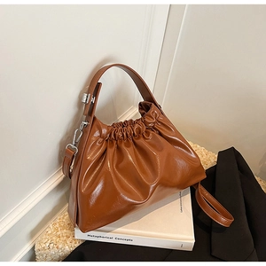 Detail of brown pleated cloud bag with shiny PU finish and silver metal hardware