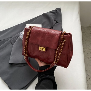 Detail of burgundy quilted leather handbag with gold chain and vintage square lock
