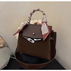 Detail of dark brown suede Kelly bag with silk scarf handle and leather lock strap