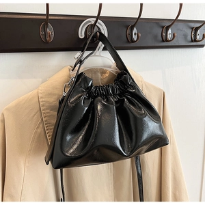 Detail of black glossy cloud bag featuring ruffled texture and silver metallic hardware