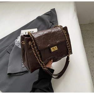 Detail of the golden metal twist lock and quilted texture on a brown chain bag