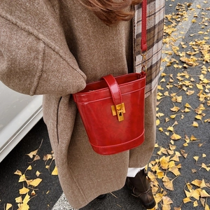 Sac seau en cuir ciré rouge avec boucle en métal doré porté par un mannequin en automne
