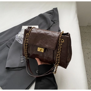 Detail view of coffee brown quilted shoulder bag with gold chain strap and metal clasp