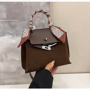Detailed close-up of dark brown suede Kelly bag with silk scarf wrapped on handle