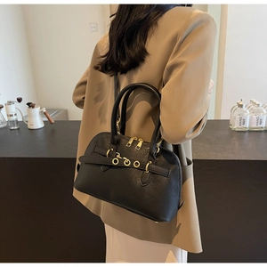 Rear view of a black grain leather Boston bag showing golden metal rings and texture