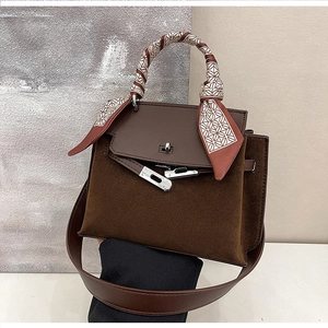 Detail of vintage matte brown Kelly bag featuring silk scarf handle and silver twist lock