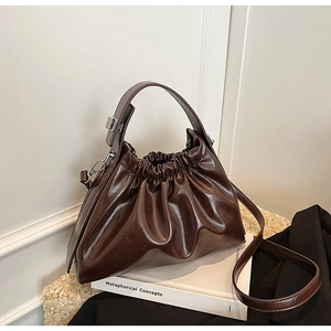 Detailed view of dark brown ruched cloud bag with glossy finish and silver hardware