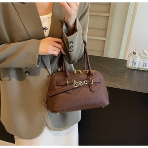 Detail of dark brown leather handbag featuring gold metal chain and textured finish
