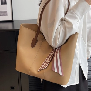 Elegant camel leather tote bag for women featuring a stylish silk scarf handle decoration