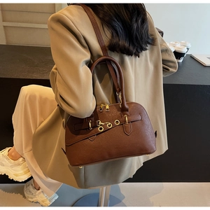Detail of dark brown leather handbag with metal ring straps and adjustable shoulder strap