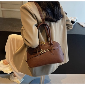 Detailed view of brown shell-shaped handbag with golden hardware and leather texture
