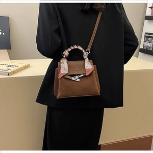 Close-up of brown frosted leather Kelly bag with silk scarf handle and silver metal clasp