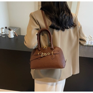 Detailed view of brown leather half-moon handbag with gold hardware and chain strap