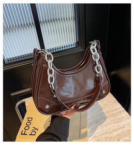 Détail du sac à main en cuir verni marron foncé avec une grosse chaîne argentée