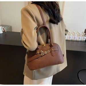 Close-up of deep brown lychee texture Boston bag with gold ring hardware and leather strap