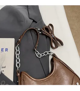 Détail d'un sac hobo marron en cuir texturé avec chaîne argentée et bandoulière