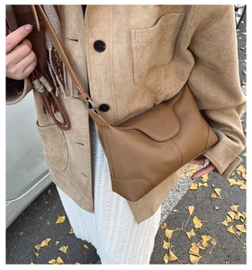 Brown lychee leather crossbody bag with flap design shown in an autumn street setting