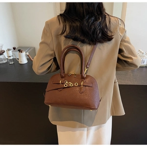 Lifestyle shot of dark brown pebbled leather crossbody bag on a model in a cozy cafe