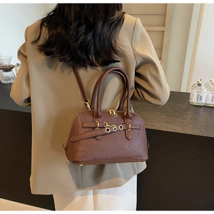 Detail of dark brown leather handbag with gold hardware and stylish leather strap buckle