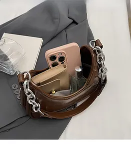 Détail montrant l'intérieur spacieux d'un sac demi-lune marron foncé avec chaîne