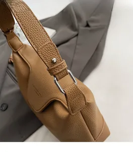 Close-up of brown litchi pattern leather texture and silver square metal hardware buckle